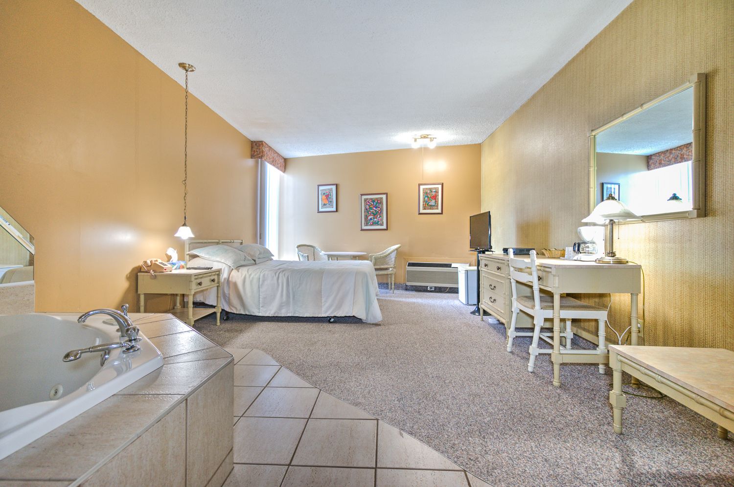 Une chambre à coucher avec un grand lit, un bureau, une chaise, une coiffeuse et une baignoire.