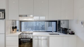 A modern kitchen with a built-in microwave, refrigerator, stove, oven, and sink. - Camberwell Serviced Apartment Hotel (Hawthorn East)