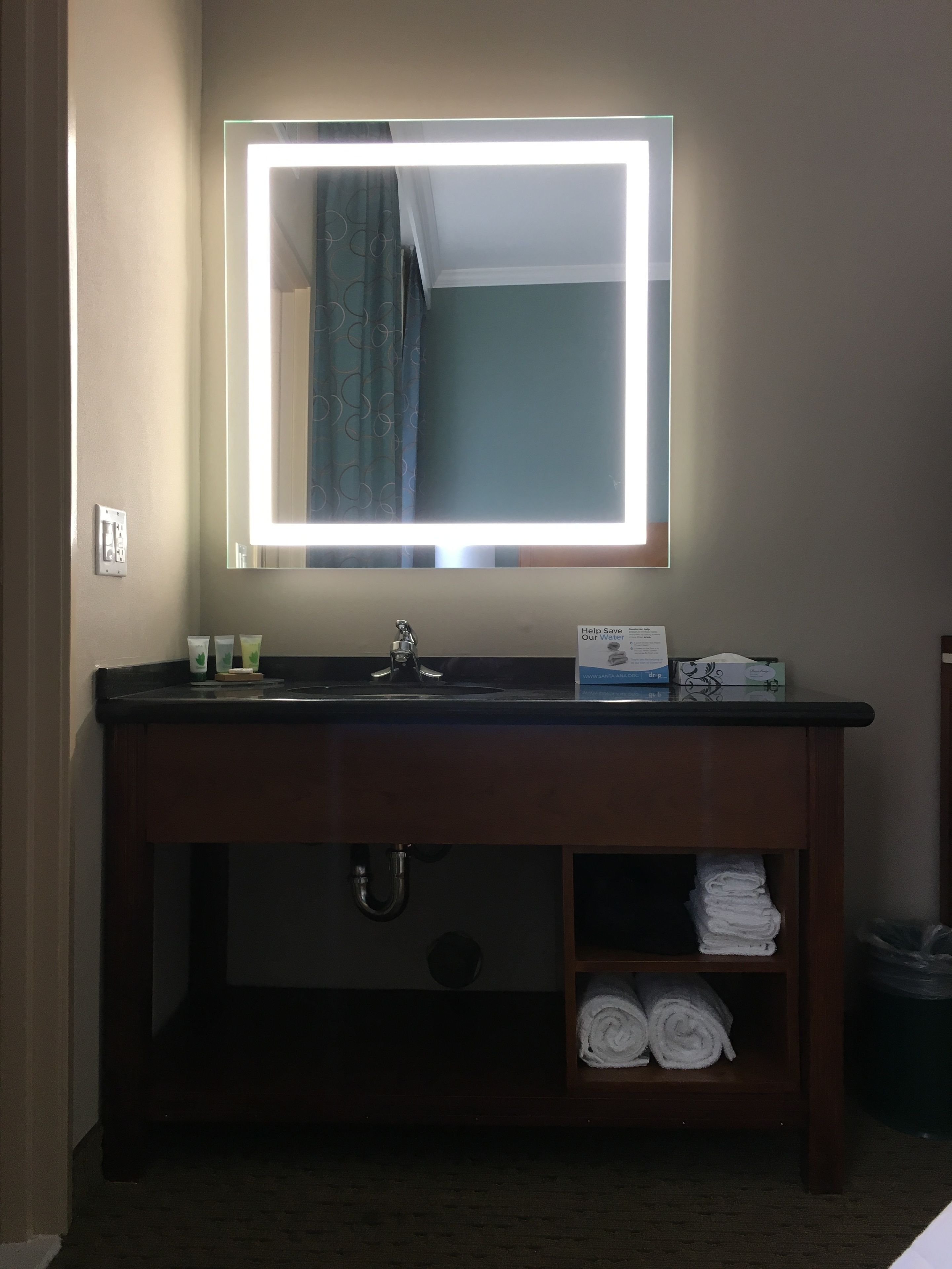 A bathroom vanity with a mirror, sink, and towel storage.