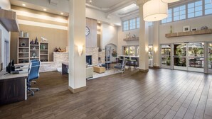 A spacious interior with a wooden floor, a reception desk, a fireplace, and a dining area with natural light.