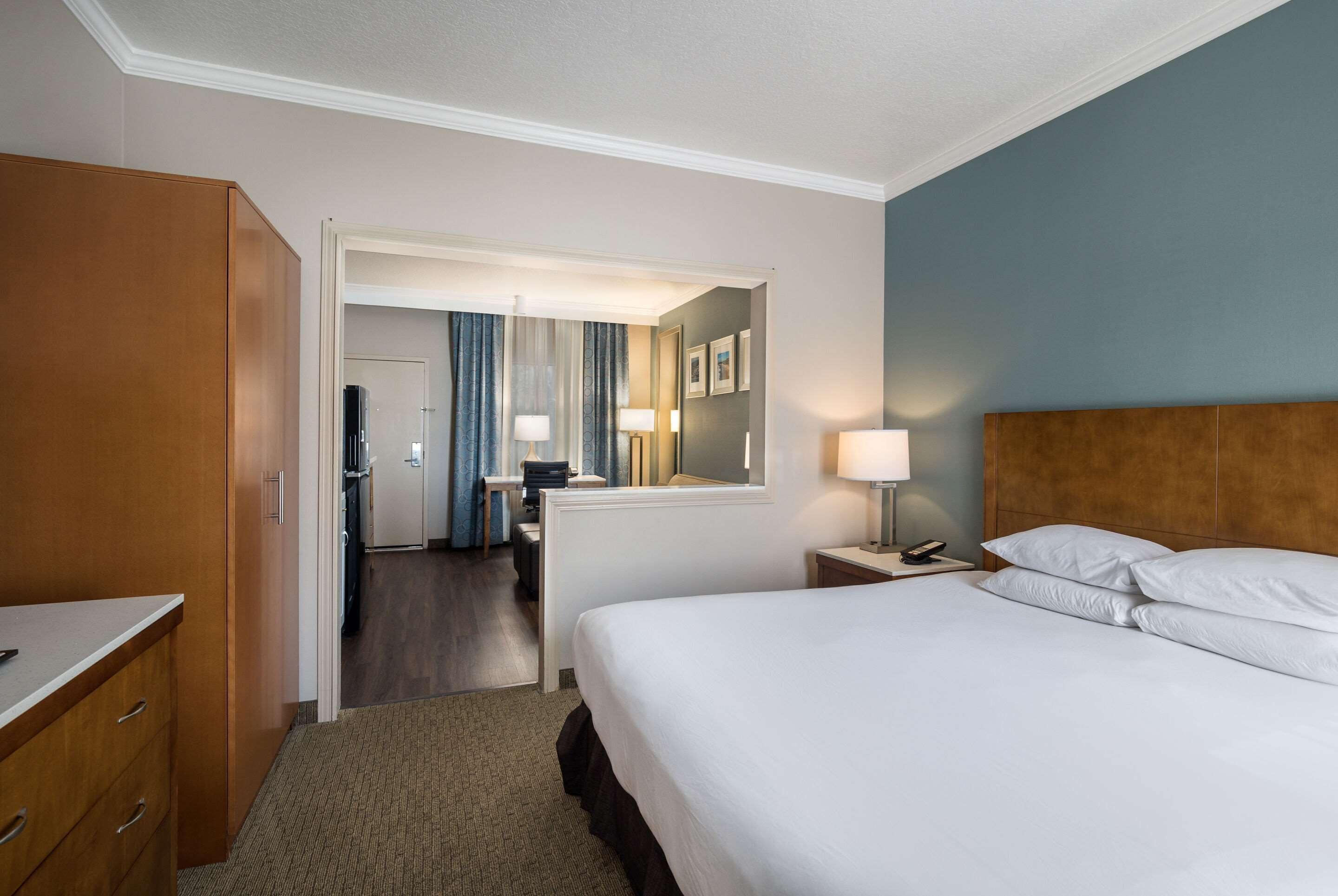 Une chambre d’hôtel avec un lit, un bureau, une armoire et une salle de bain visible à travers une porte ouverte.