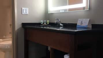 A bathroom with a sink, mirror, and towel rack.
