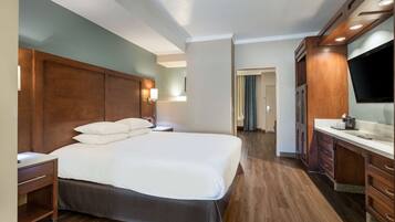Hotellihuone, jossa on suuri sänky, puinen pääty, televisio ja puinen peilipöytä.