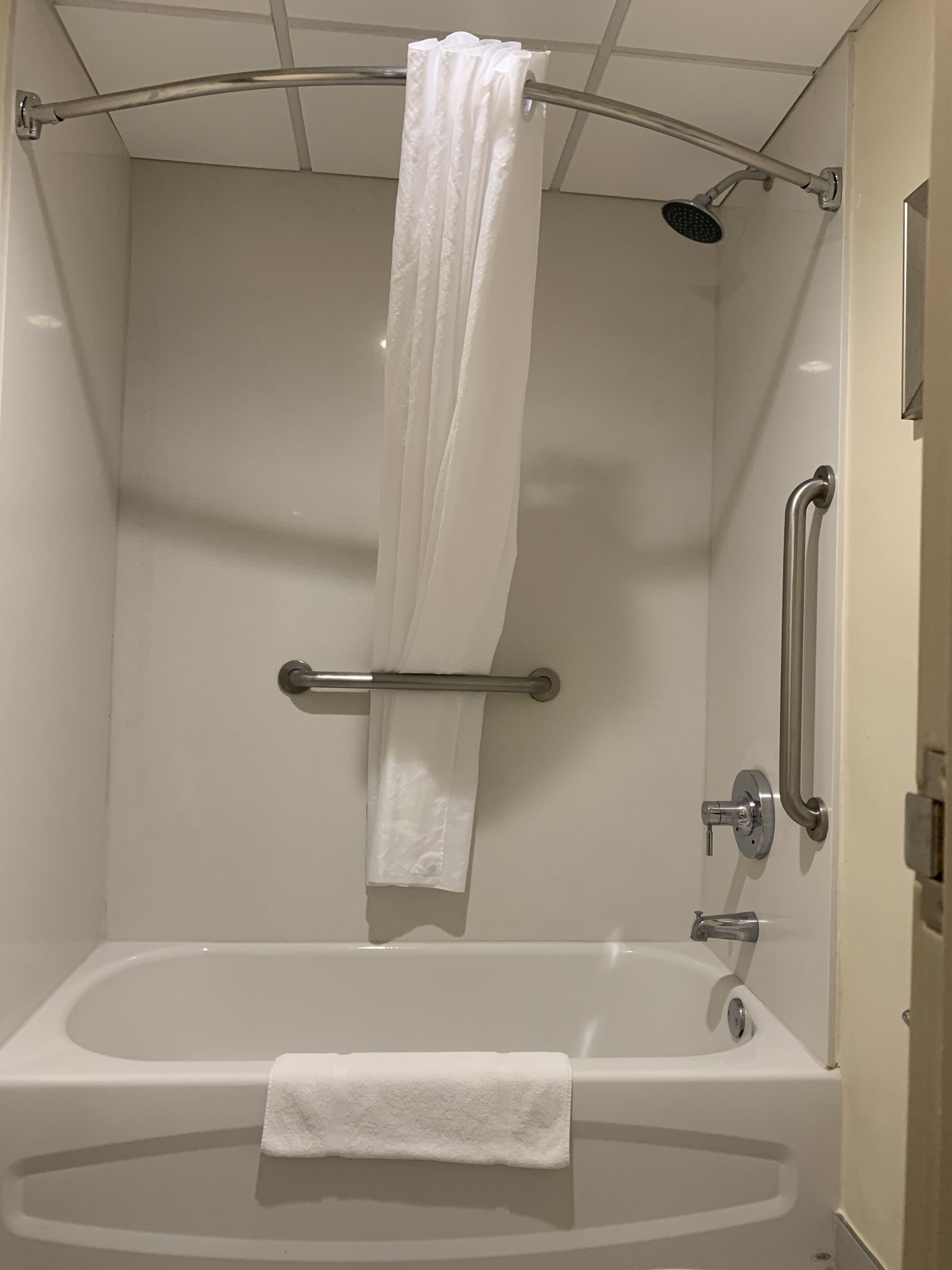 A modern bathroom with a bathtub, a showerhead, and a grab bar.