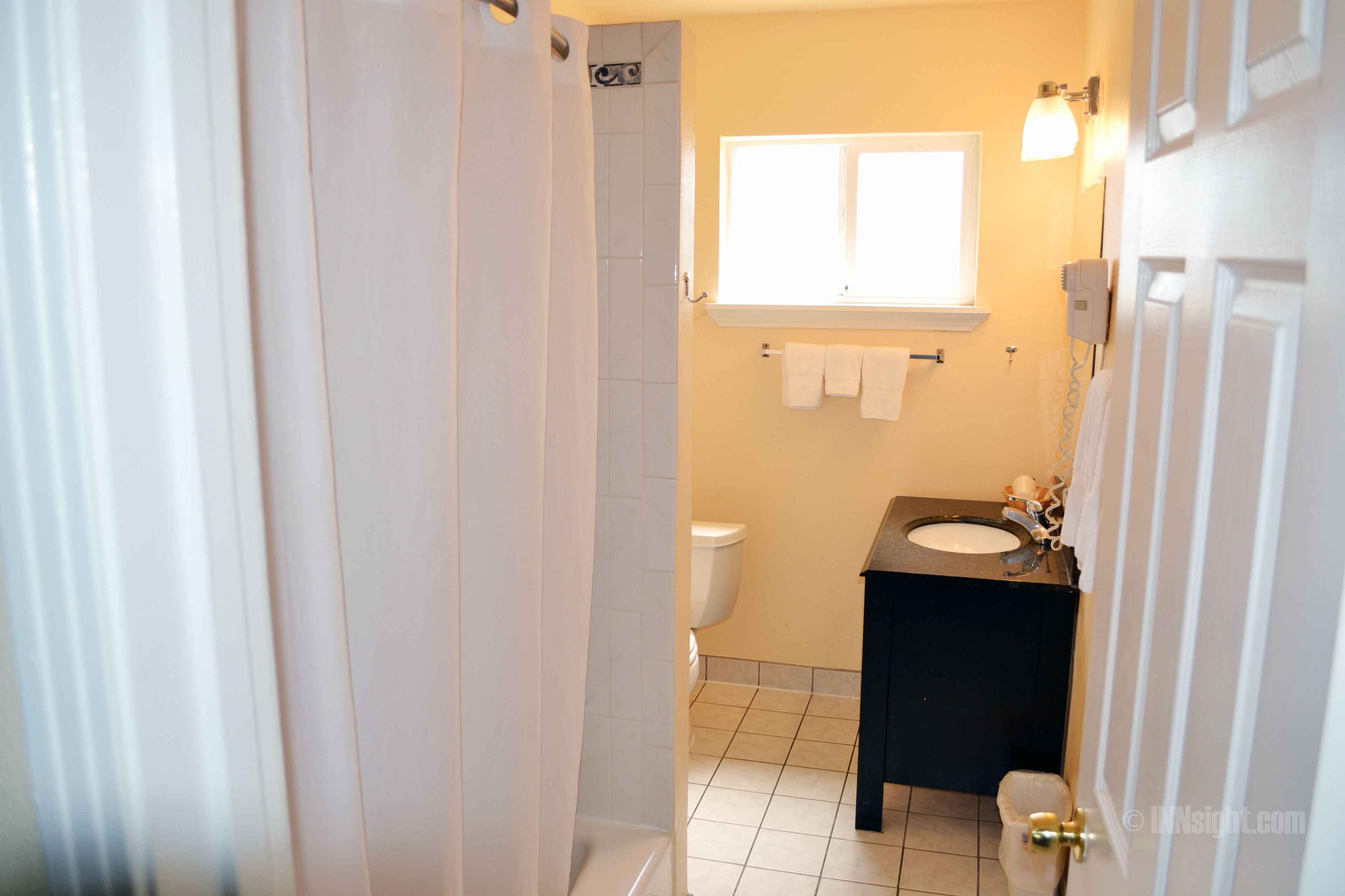Ein Badezimmer mit Dusche, Toilette, Waschbecken und einem Fenster über dem Waschbecken.