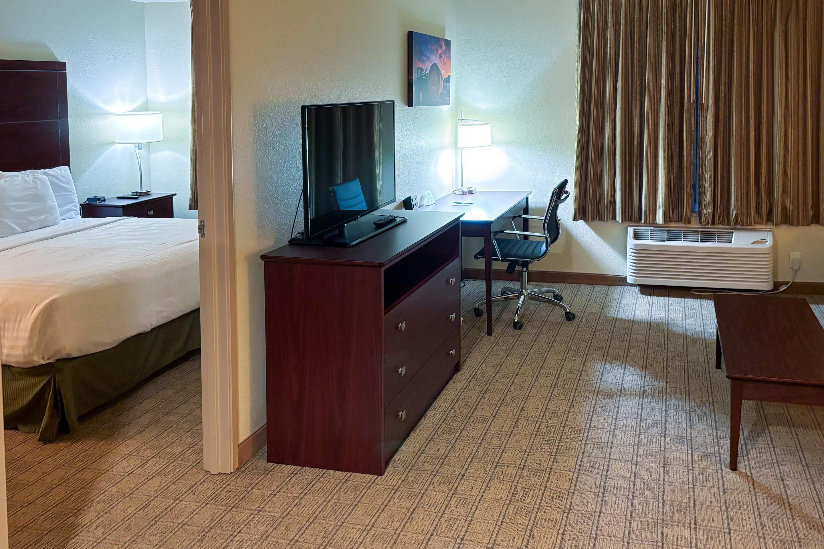 Une chambre d’hôtel comprenant un lit, un bureau avec un ordinateur, une chaise, une commode et un appareil de climatisation.