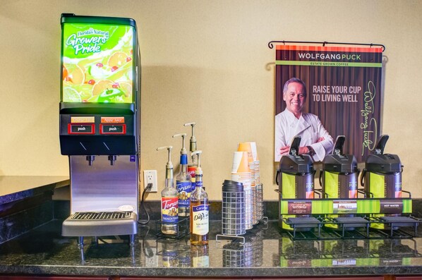 A coffee machine, a beverage dispenser, and a coffee station with a banner.