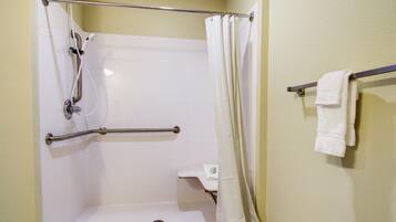 A shower with a grab bar, a white towel rack, and a shower curtain.