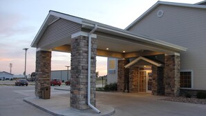 A building with a covered entrance, stone pillars, and a clear sky. - Castle Rock Inn & Suites (Quinter)