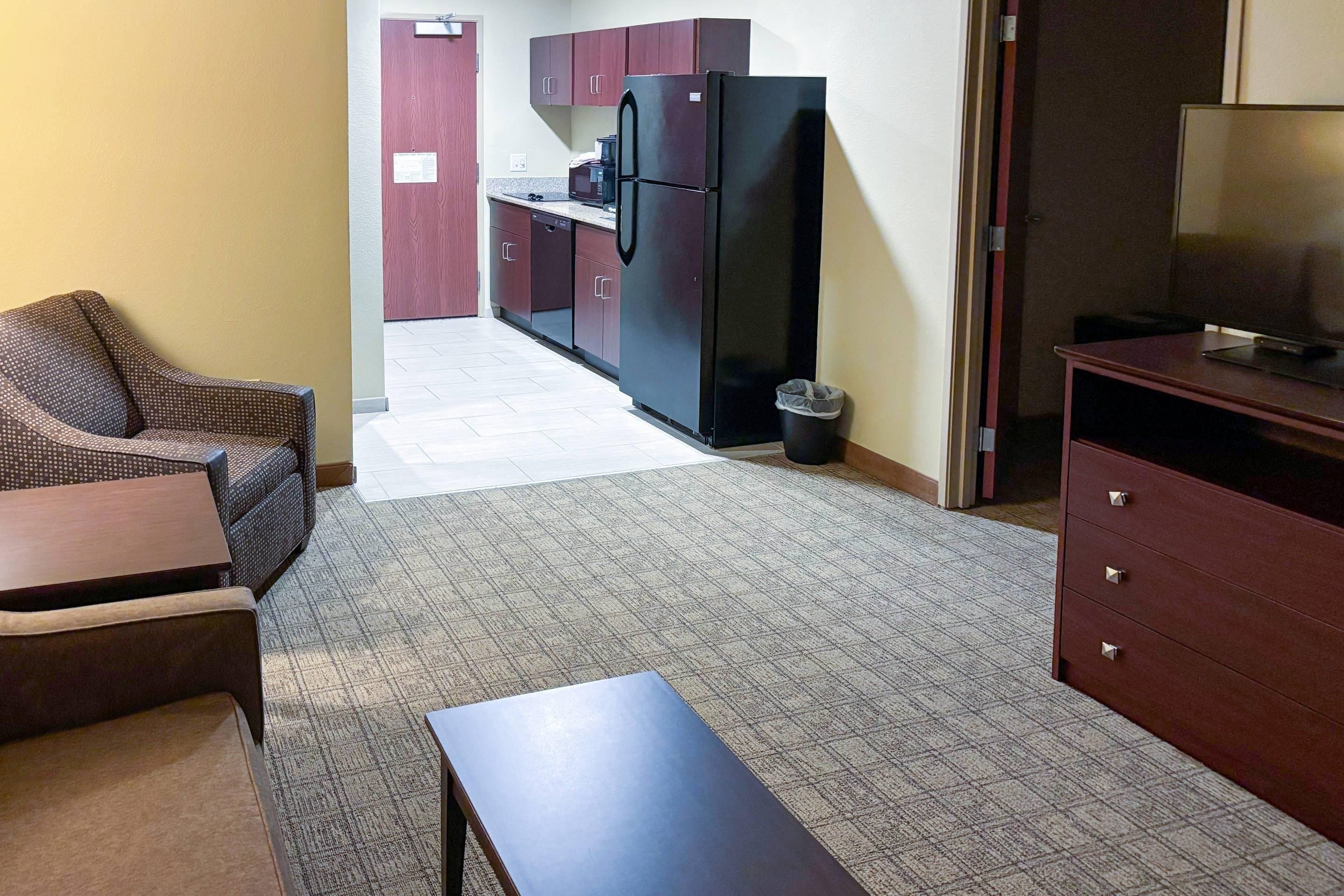 A compact living space with a kitchenette, a dining area with a table and chairs, and a small TV on a stand.