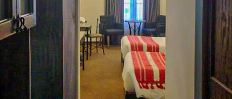 A hotel room with a bed, a desk, a chair, and a ceiling fan.