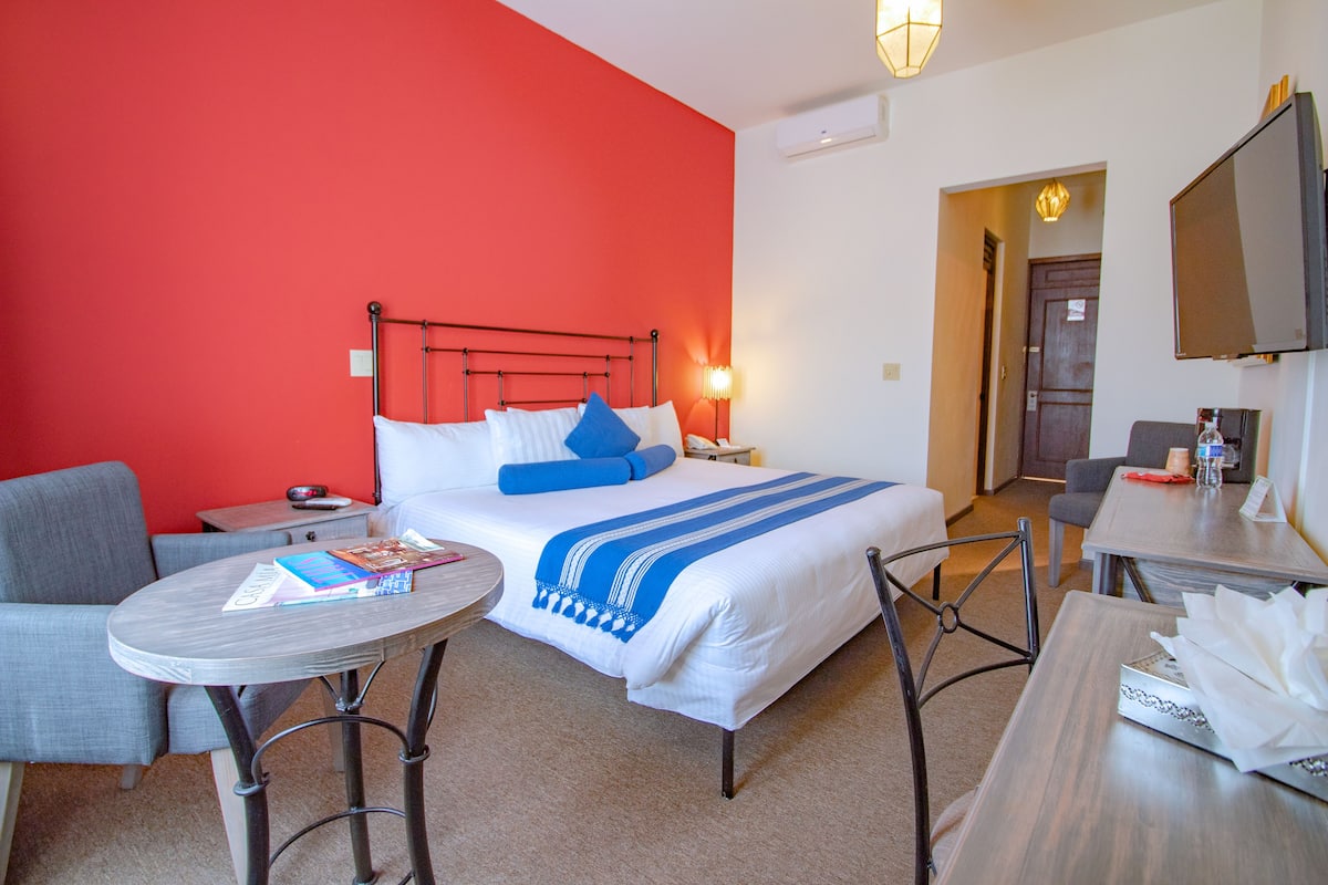 Una habitación de hotel con cama, escritorio, silla, mesa y televisor.
