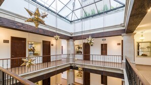 Ein mehrgeschossiges Atrium mit Glasdecke, Holzwertungen und hängenden Sterndekorationen.