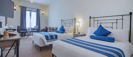 A hotel room with two beds, a desk, a chair, a TV, and a window with curtains.