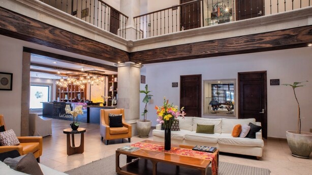 Eine großzügige Lobby mit hoher Decke, einem Empfangsbereich, Sitzgelegenheiten und einer Treppe.