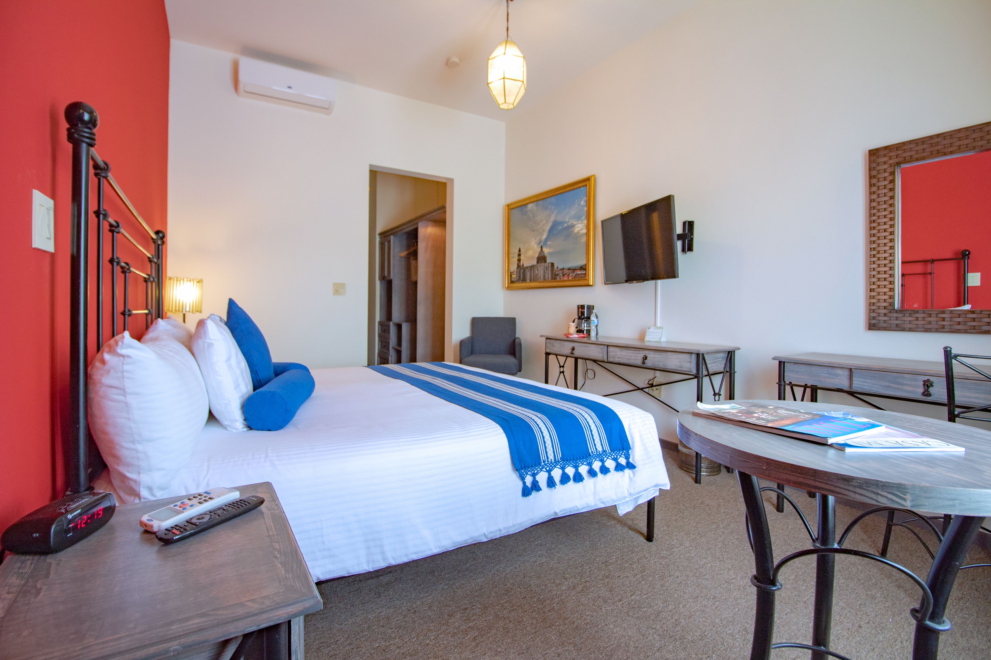 Una habitación de hotel con cama, mesita de noche, escritorio y una silla.