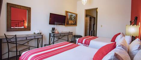 Habitación de hotel con dos camas, un escritorio, una silla, un televisor y un ventilador de techo.
