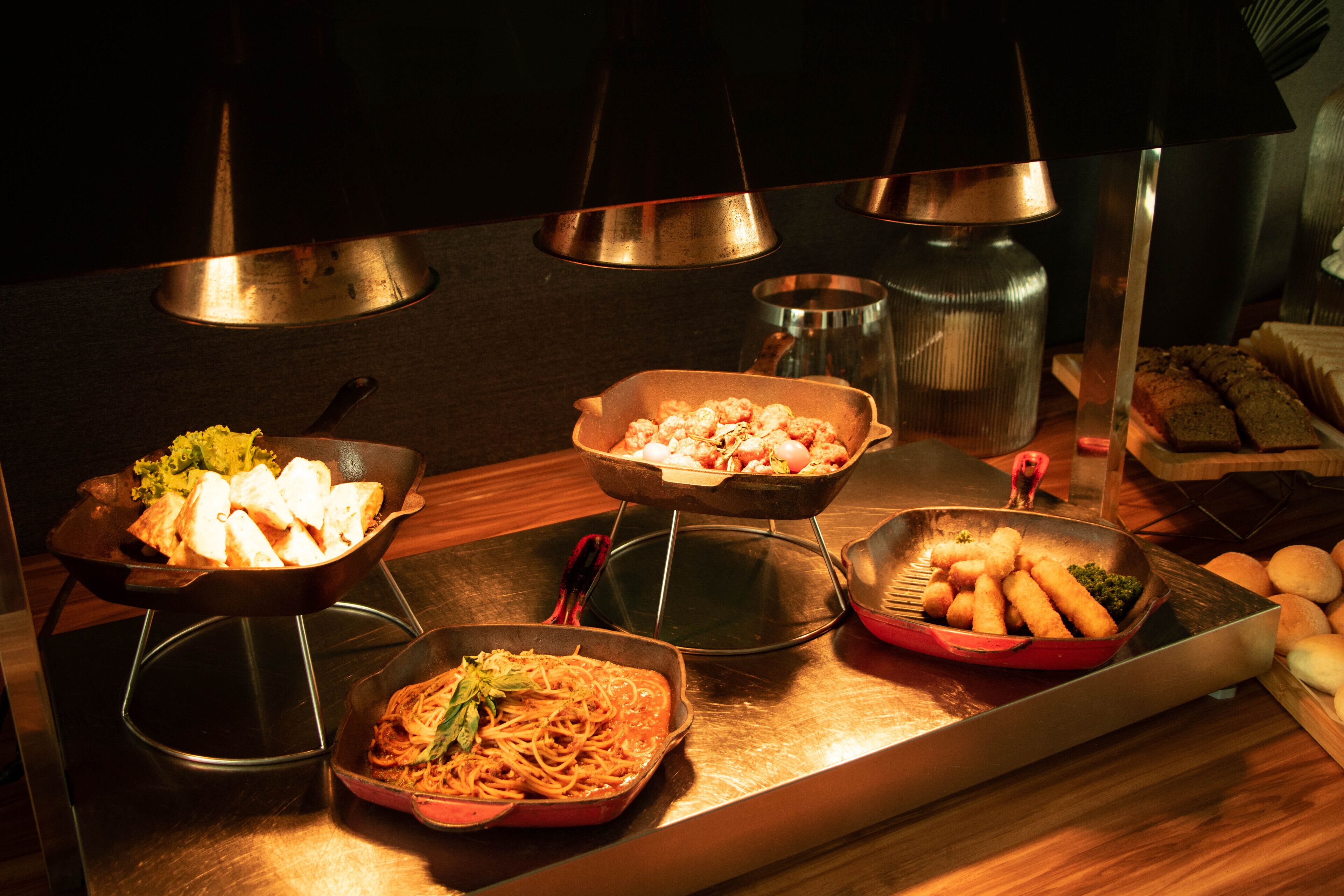 A buffet table with various dishes including pasta, seafood, and bread.