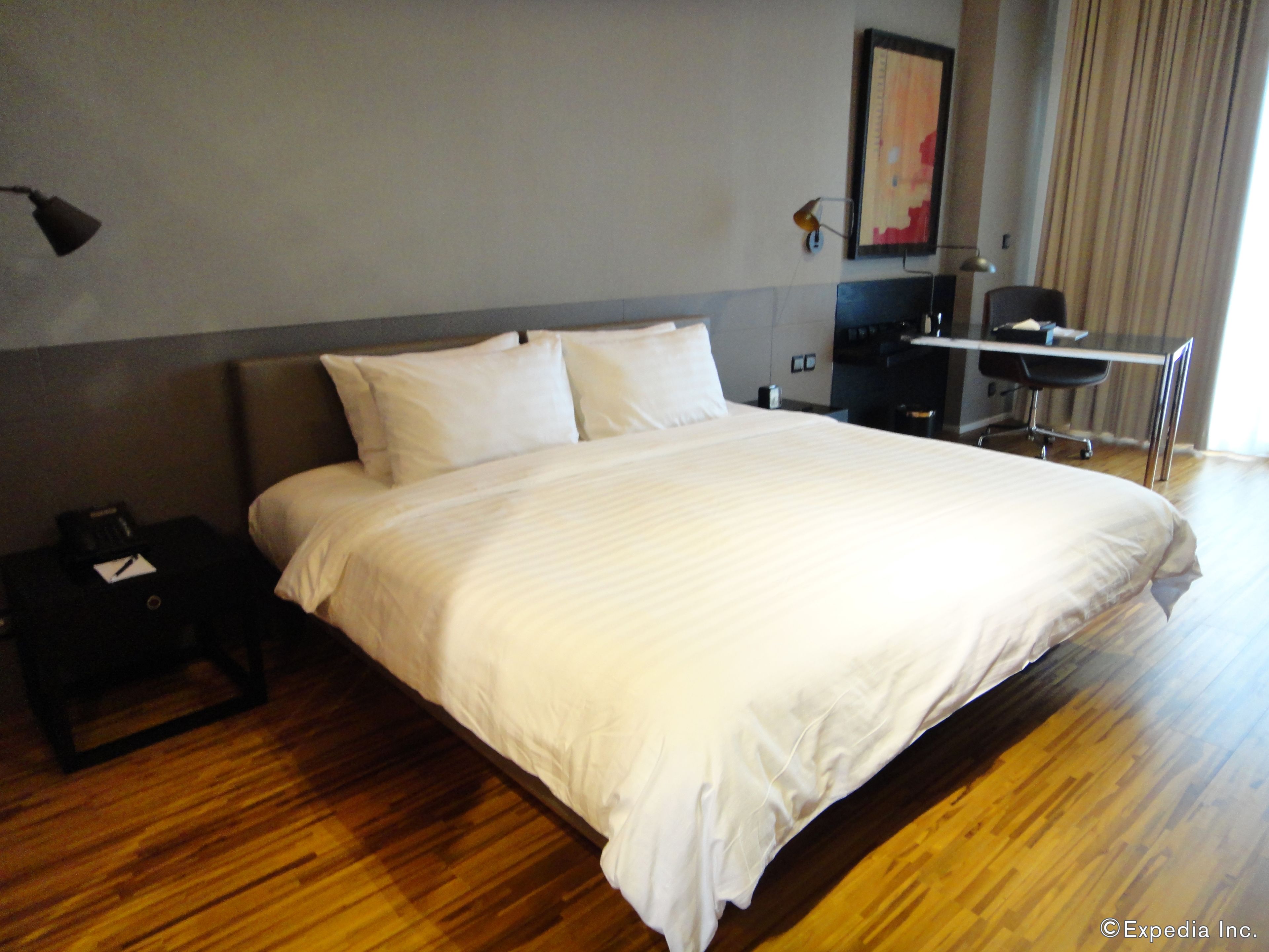 A hotel room with a large bed, a desk, and a chair.