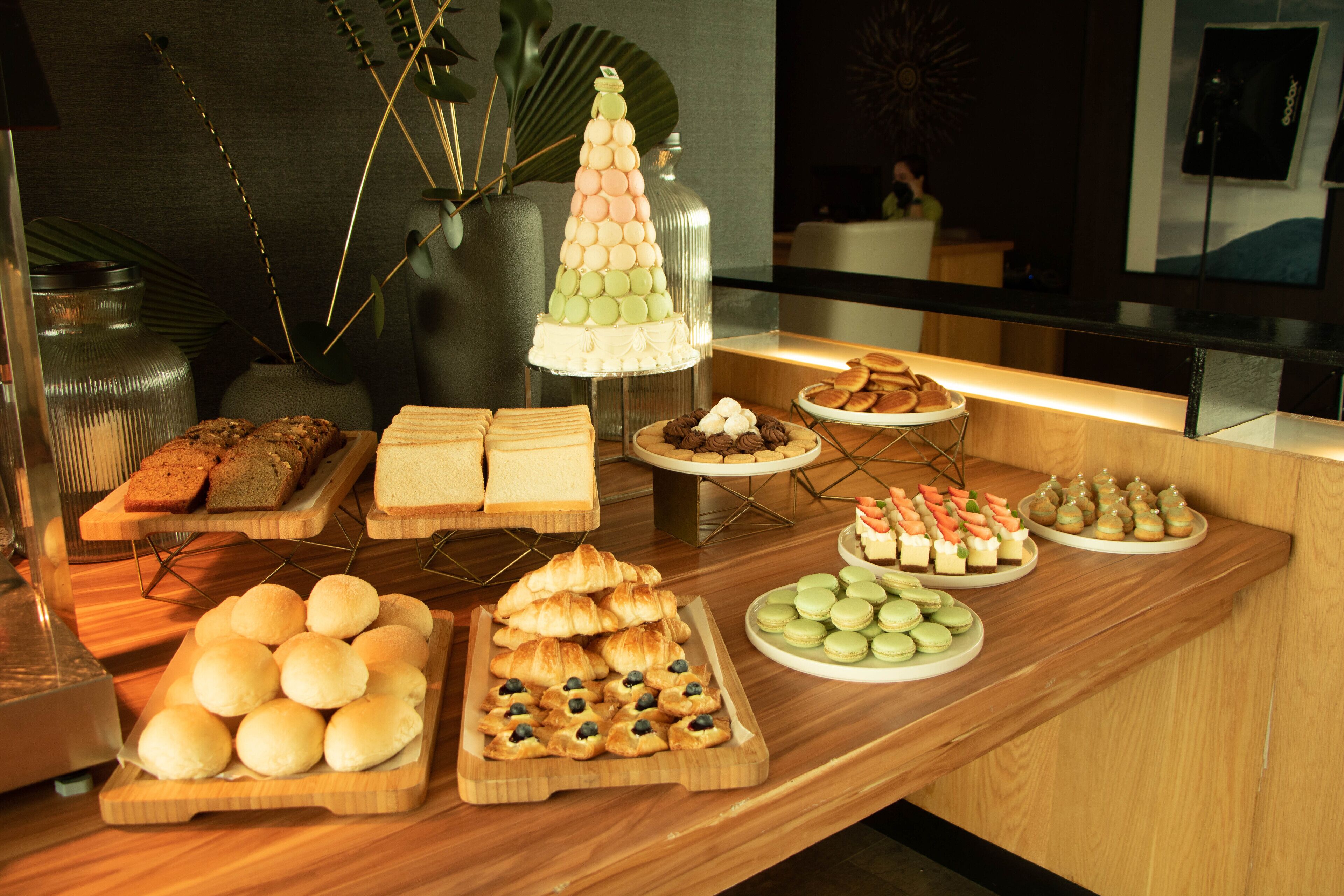 Un buffet proposant une variété de viennoiseries, de sandwichs et de desserts.