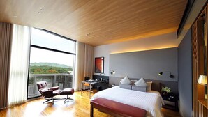 A modern hotel room with a large bed, a desk, and a view of the outdoors.