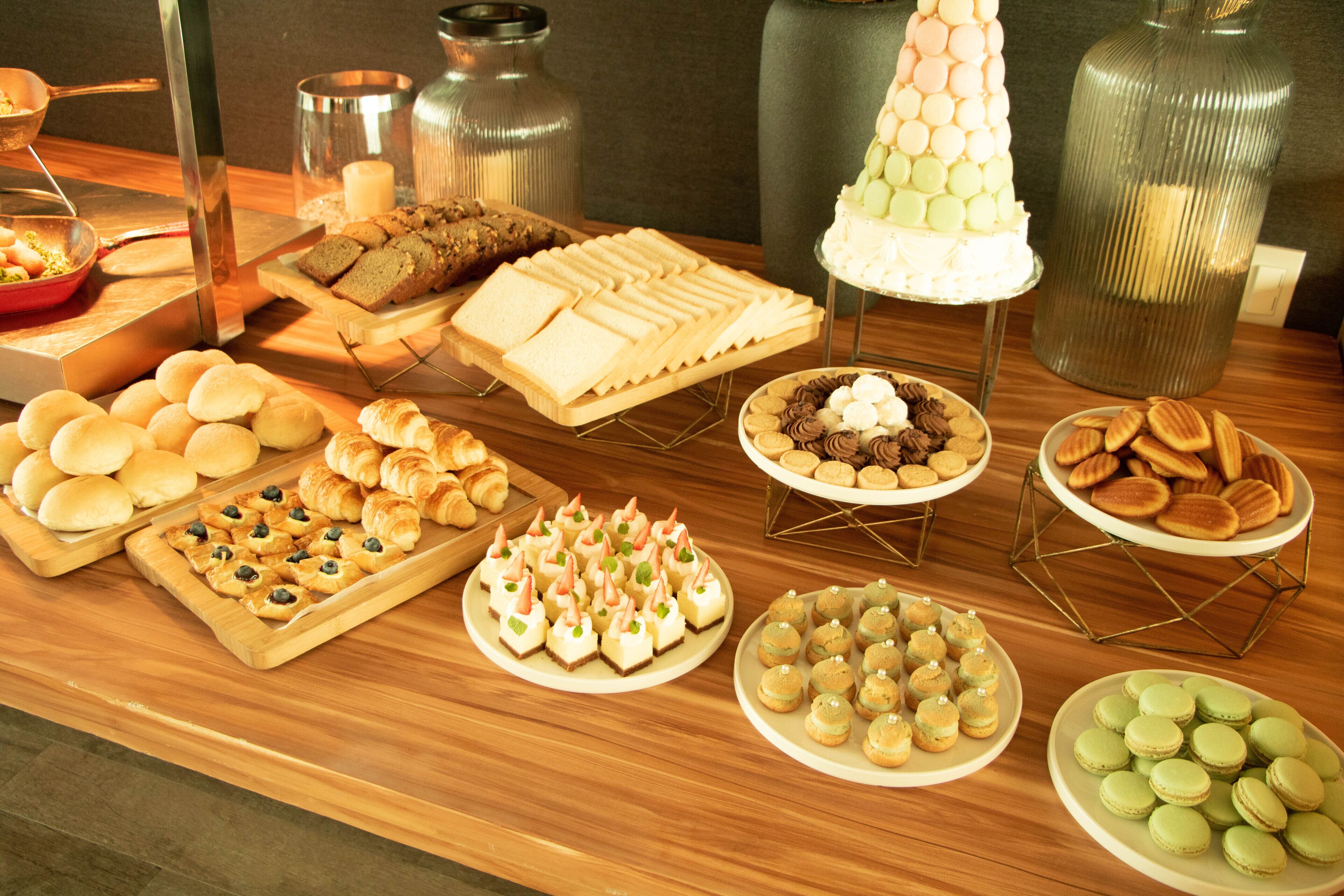 A buffet table with various food items including bread, pastries, and desserts.