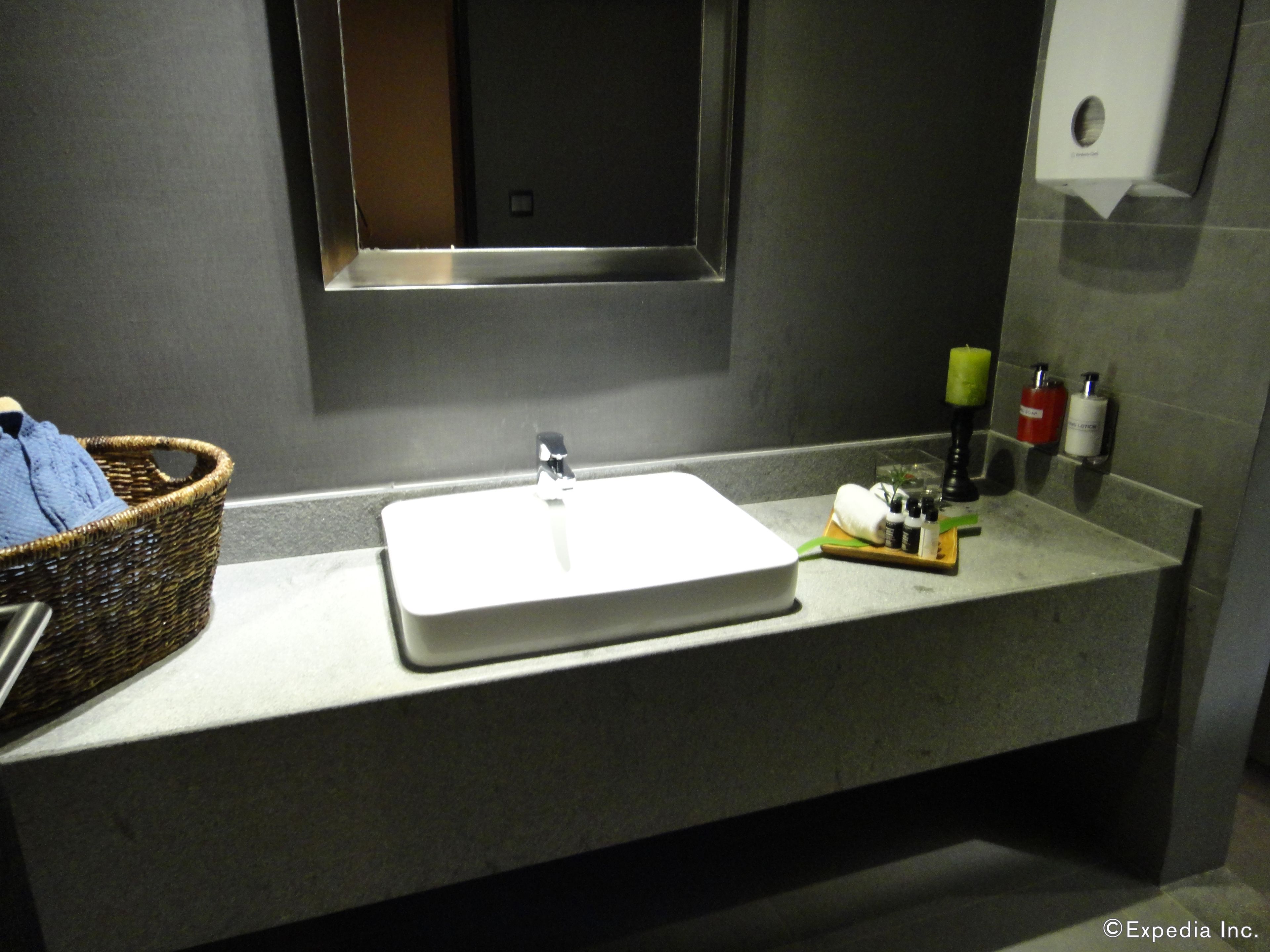 A bathroom with a white sink, a mirror, a wicker basket, and toiletries on the counter.