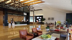 A spacious lobby with a reception desk, seating areas, and a modern chandelier.