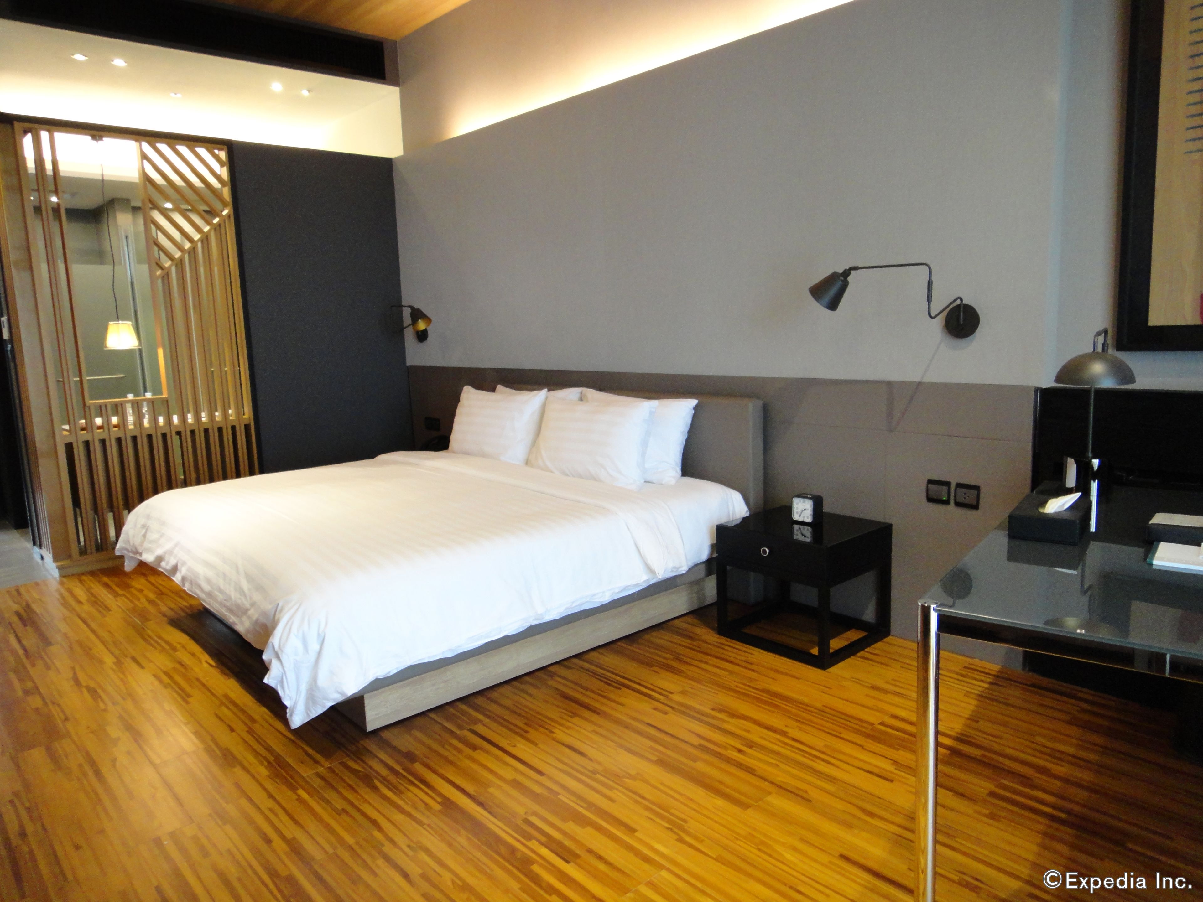 Habitació d'hotel moderna amb un llit gran, una tauleta de nit, un escriptori i un mirall.