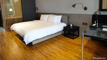 Habitació d'hotel moderna amb un llit gran, una tauleta de nit, un escriptori i un mirall.