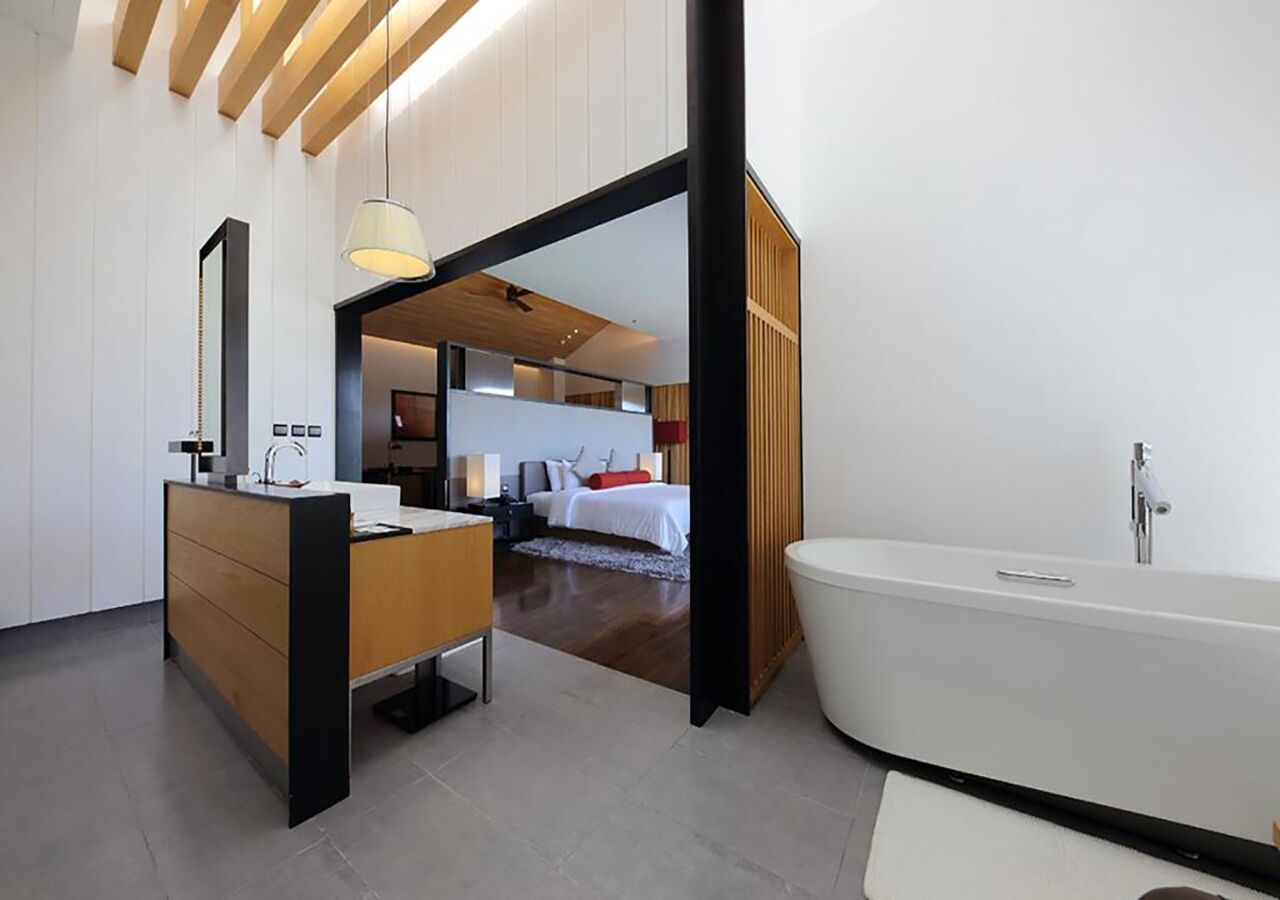 Un baño moderno con una bañera independiente, un mueble de tocador de madera y un espejo grande.