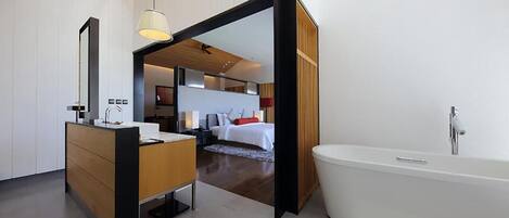 Un baño moderno con una bañera independiente, un mueble de tocador de madera y un espejo grande.