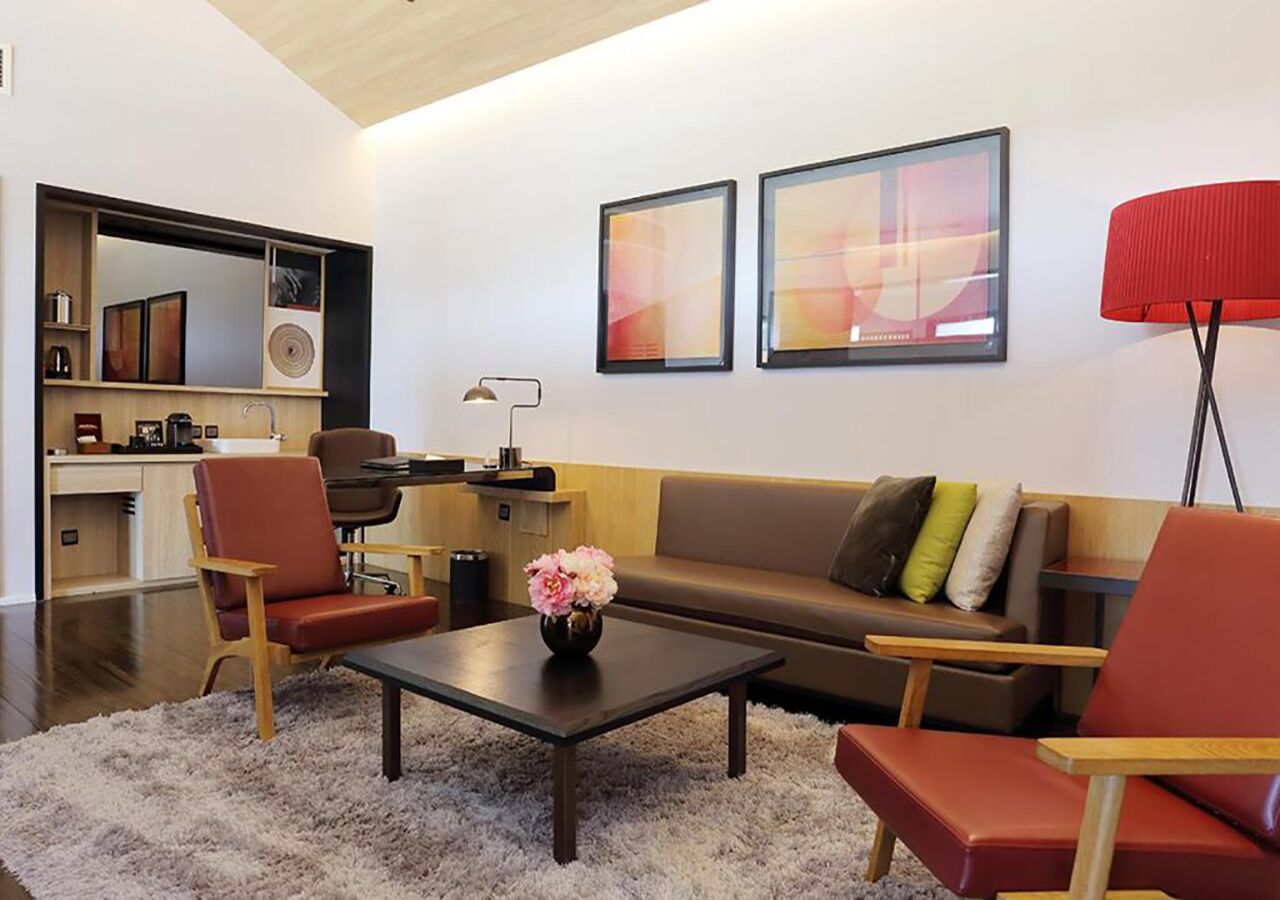 A modern living room with a sofa, chairs, a coffee table, and artwork on the wall.
