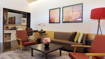 A modern living room with a sofa, chairs, a coffee table, and artwork on the wall.