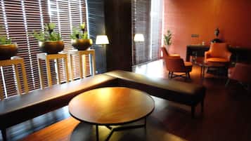 A modern interior with a round wooden table, seating area, and potted plants.