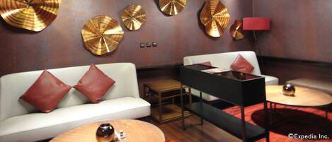 A modern interior with a white sofa, red pillows, a black side table, and a round table with a decorative sphere.