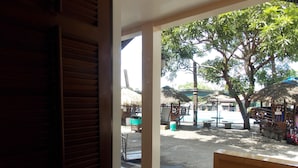 Vista dalla finestra di una stanza con affaccio su un'area esterna, una piscina, ombrelloni e posti a sedere.