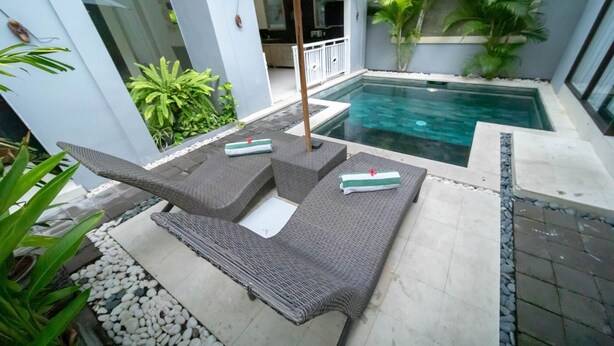 A poolside area with wicker lounge chairs, a small pool, and surrounding greenery. - Bahagia Villas (Denpasar)