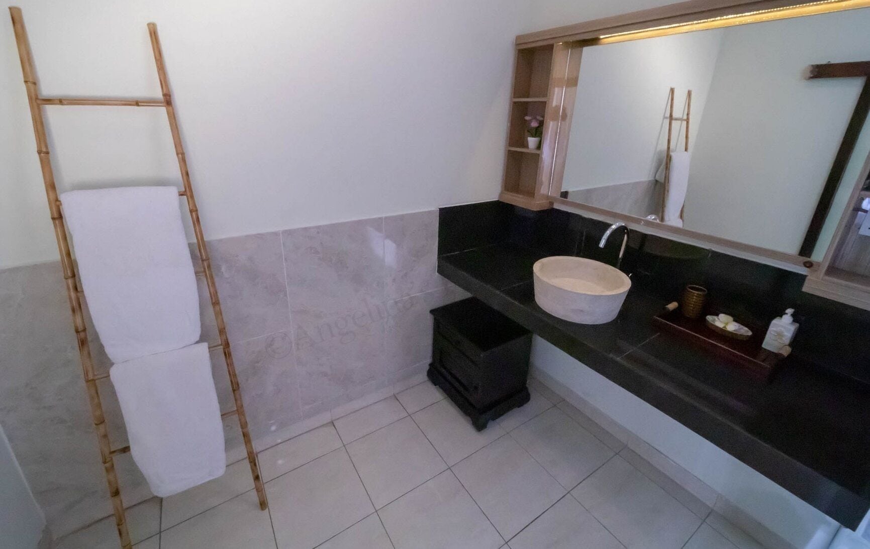 A bathroom with a bamboo ladder, a white sink, and a mirror with a shelf.