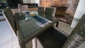 A dining table with a glass top and wicker chairs in a modern kitchen setting. - Bahagia Villas (Denpasar)