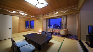 Una habitación tradicional japonesa con suelo de tatami, una mesa baja y un televisor.