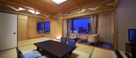 A traditional Japanese-style room with tatami flooring, a low table, and a TV.