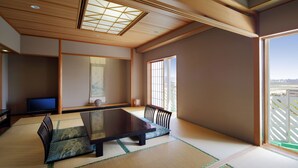 Una habitación tradicional japonesa con suelo de tatami, una mesa baja y un televisor.