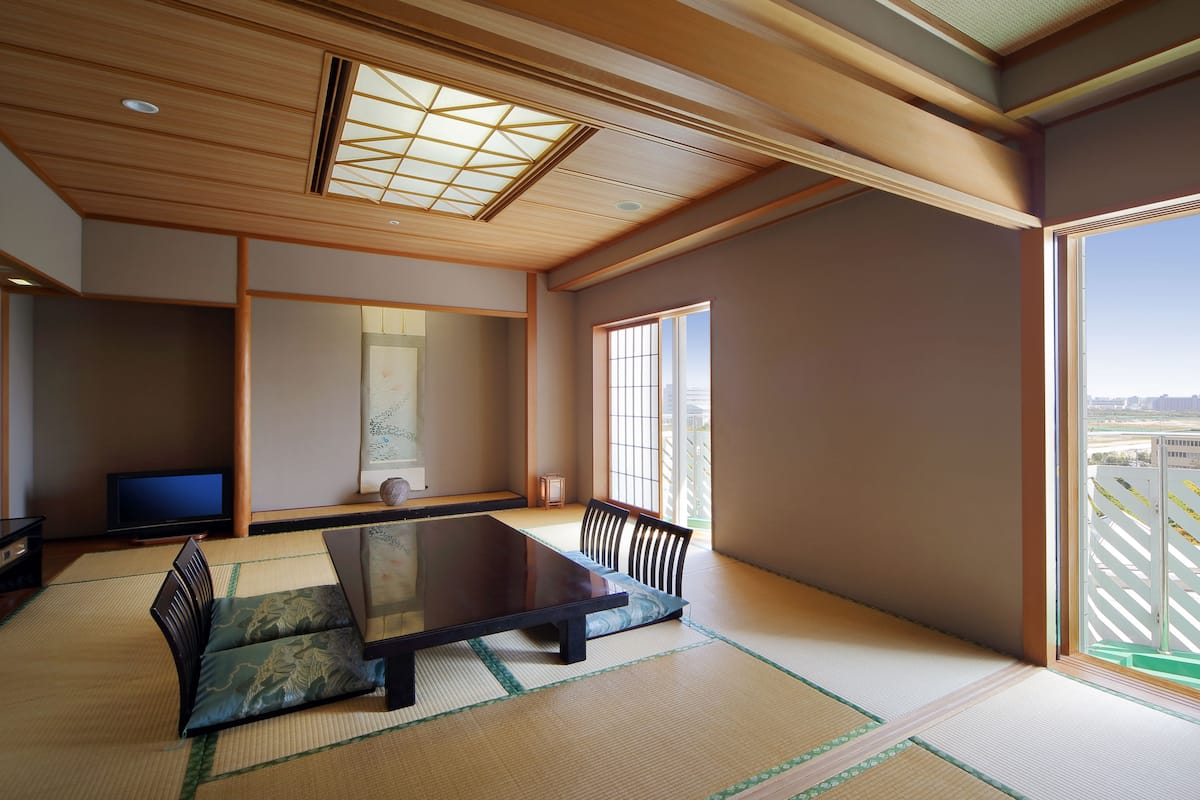 A traditional Japanese room with tatami flooring, a low table, and a television.