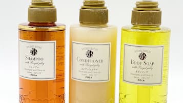 Three bottles of shower products with pumps, each labeled with different names and containing royal jelly and olive oil.