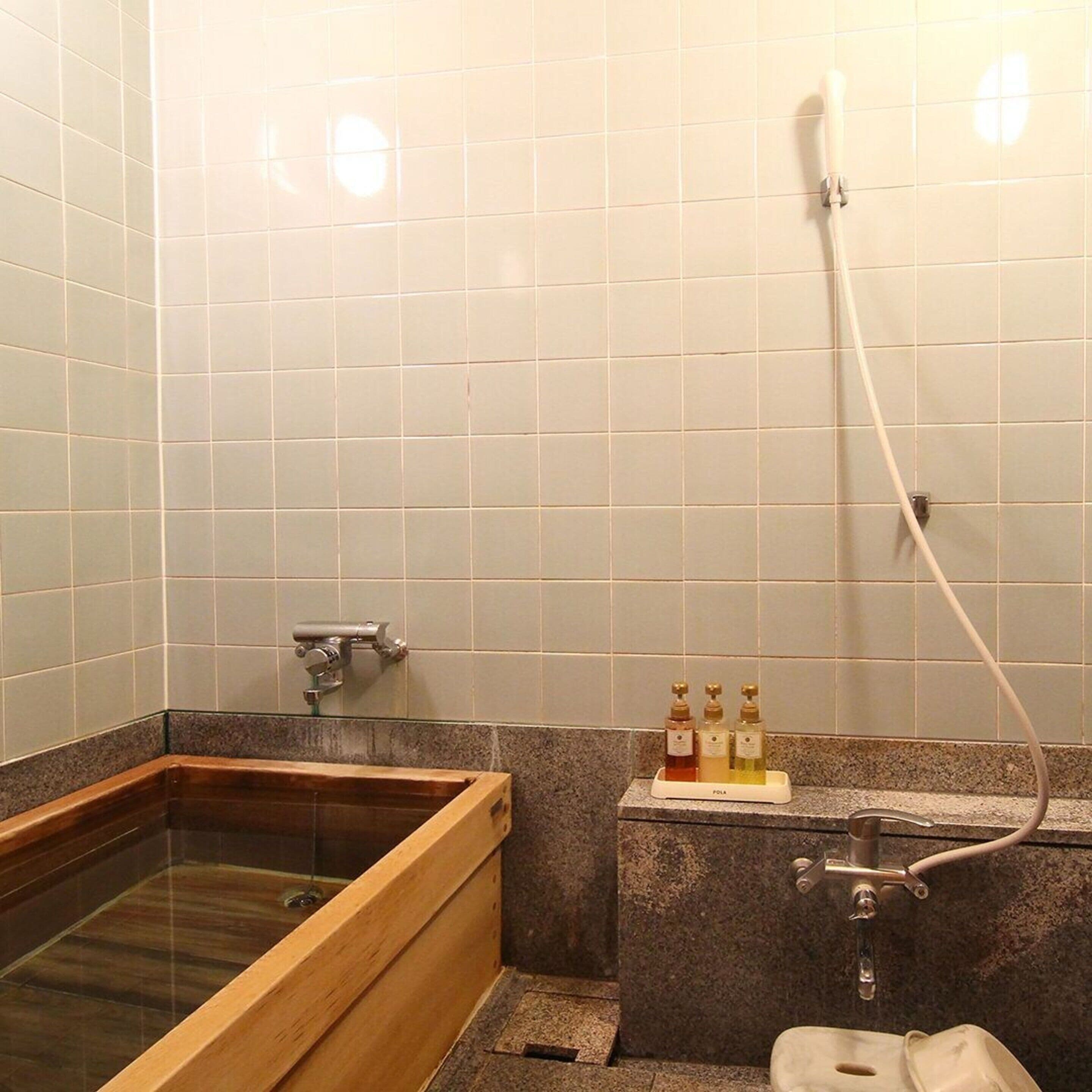 Een badkamer met een houten bad, een wastafel met een kraan en een douchekop.