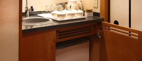 A compact kitchenette with a sink, a small refrigerator, and a countertop with kitchenware.