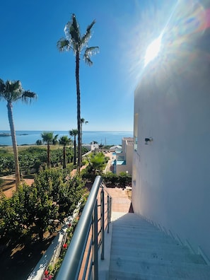 A staircase leading to a balcony overlooking a pool and a view of the sea. - Saradari Beach Hotel - Adults Only (Hersonissos)