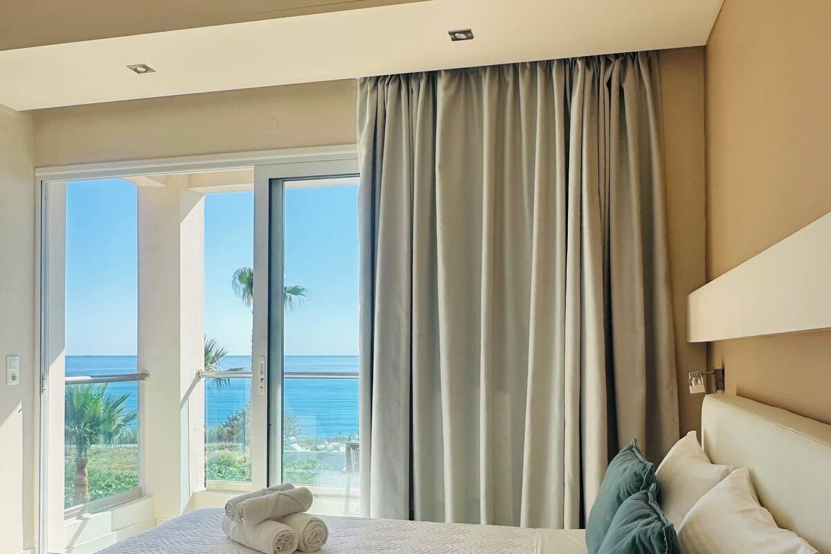 A hotel room with a large bed, a view of the ocean, and a balcony.