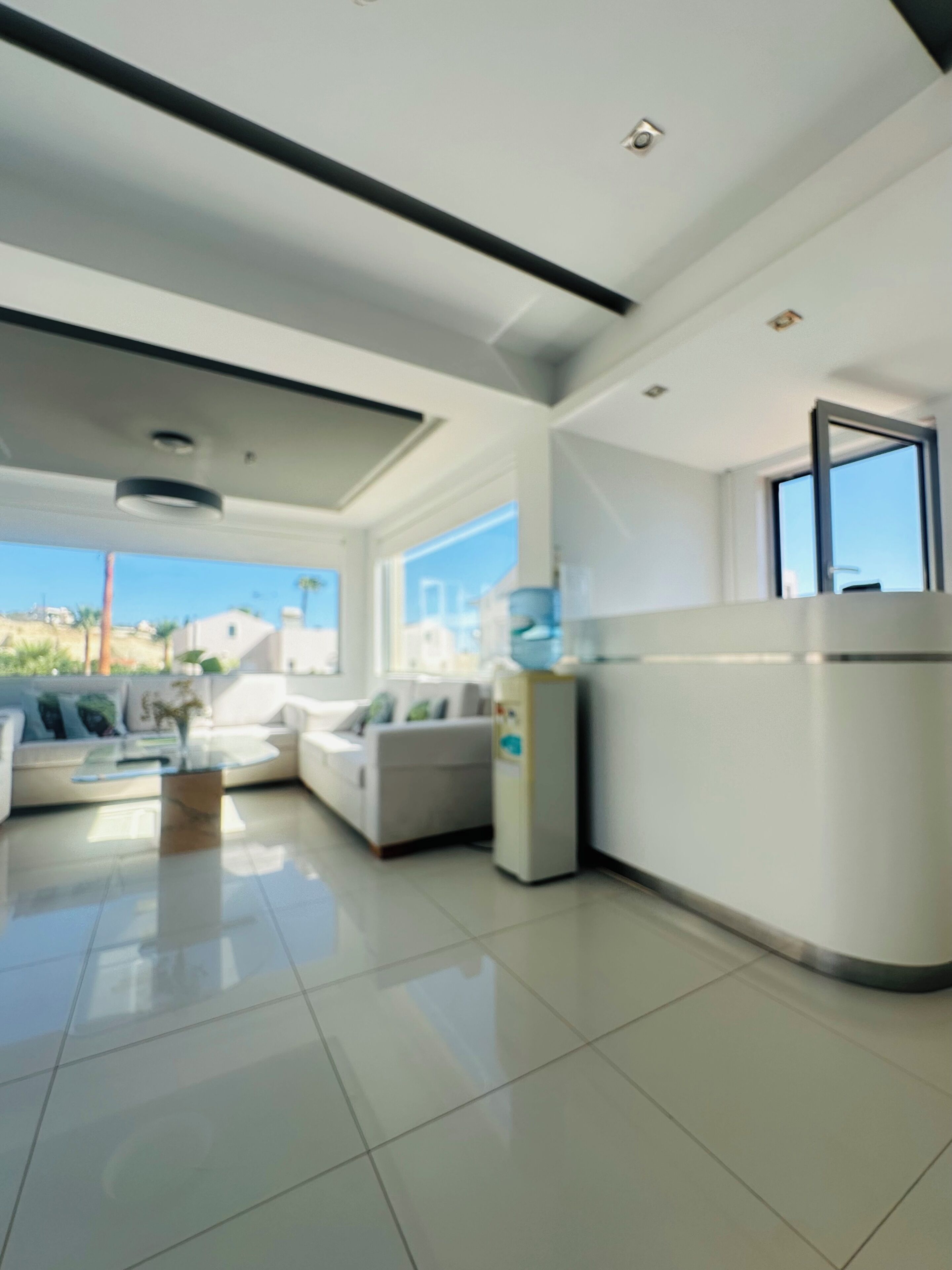 A modern living room with a sofa, a coffee table, and a kitchen area with a refrigerator.